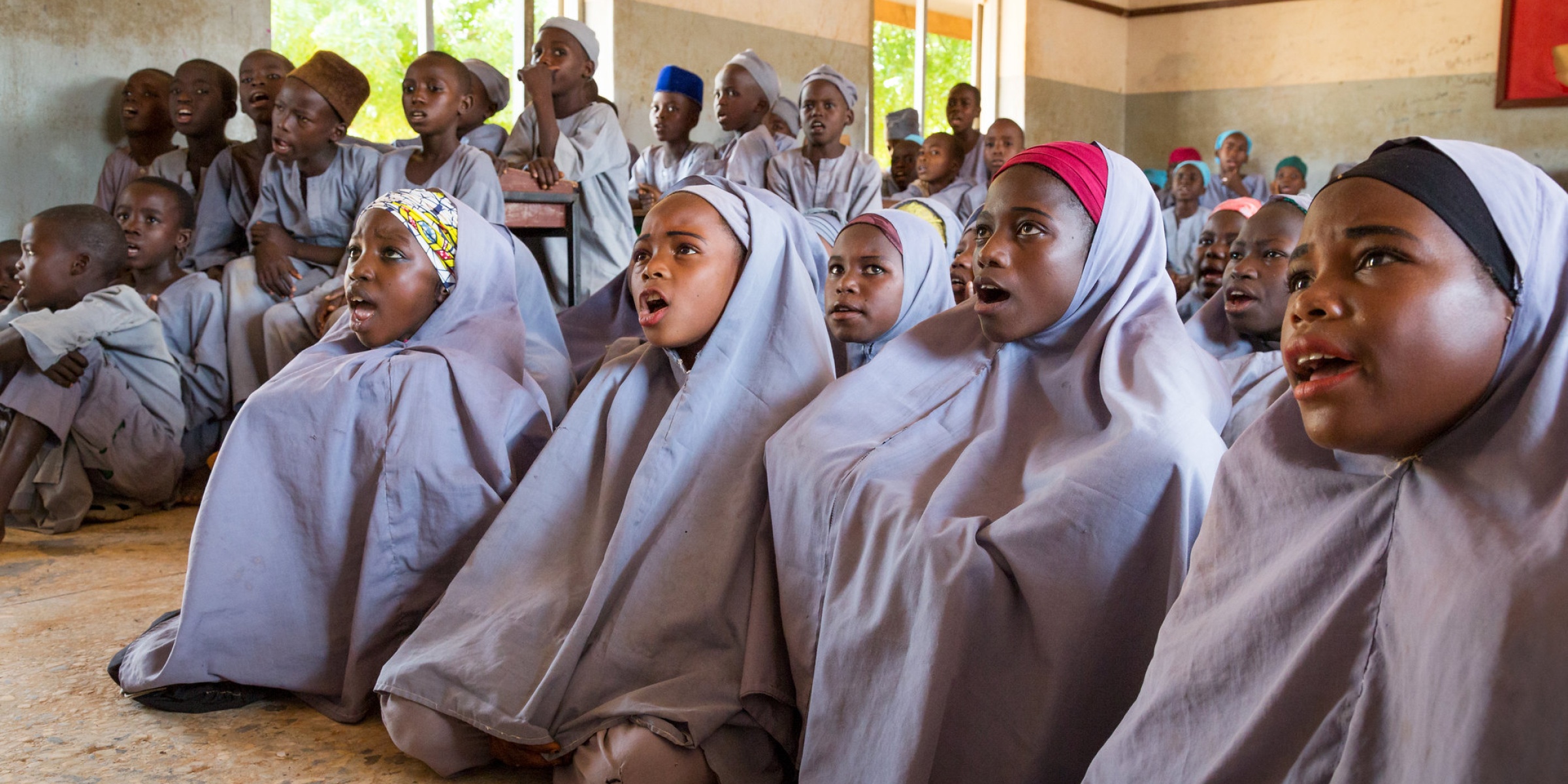 Sumayya Ado, 13 (second from right), and other girls sit on the floor at Janbulo Islamiyya Primary School, Roni, Jigawa State, Nigeria.  Asked if she could change one thing about the school, she says, “I would add more classrooms. Our classes are too congested.” Credit: GPE/Kelley Lynch